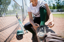 Middle School Girl Softball Player Tying Shoe On Bench