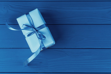 Gift box with ribbon on blue background, top view