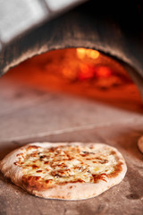 Wall Mural - Baked tasty margherita pizza in Traditional wood oven in Naples restaurant, Italy. Original neapolitan pizza. Red hot coal.