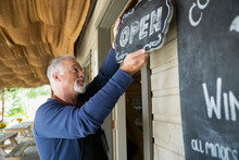 Senior Male Vintner Hanging Open Sign At Winery Tasting Room