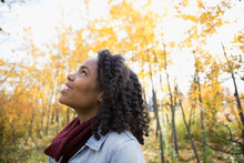 Curious Woman With Curly Black Hair Looking Up In Autumn Woods