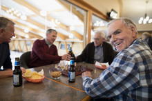 Portrait Smiling Senior Man Playing Chess And Drinking Beer With Friends At Curling Club