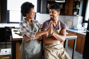 Beautiful young couple having fun and laughing while cooking in kitchen