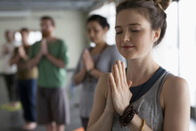 Serene Woman With Eyes Closed And Hands At Heart Center In Yoga Class Studio