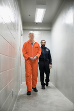 Bailiff Walking Prisoner In Orange Jumpsuit Down Corridor In Jail
