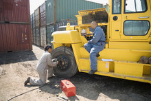 Mechanics Fixing Heavy Machinery In Sunny Industrial Container Yard