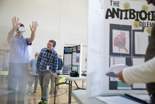 Middle School Student Son Watching Father Using Virtual Reality Simulator Glasses At Science Fair