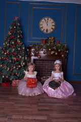 two sisters in white with pink dress sitting with gifts in hands