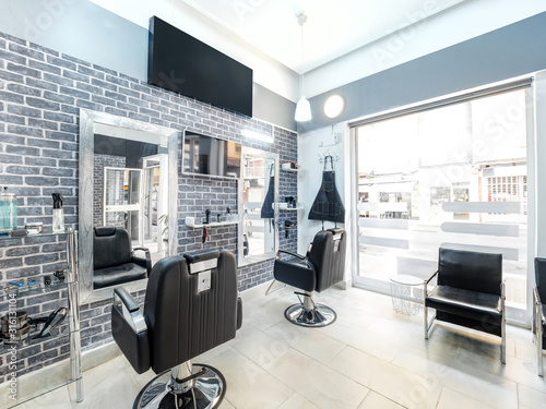 Modern bright beauty salon. Hair salon interior business with industrial minimal look. Black and white decoration with mirrors, chairs,tv screen and mockup banners