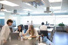 Female Professor And College Students Conducting Scientific Experiment In Laboratory Classroom