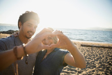 Affectionate Couple Forming Heart-shape With Hands On Sunny Ocean Beach