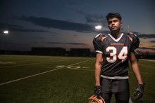 Portrait Serious, Tough Teenage Boy High School Football Player On Football Field At Night