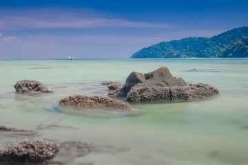 view of arch rocks on smooth silky blue-green sea with blue sky background. (Long Exposure Technic) Khao Chong Kad, Surin island, southern of Thailand.