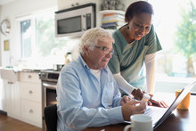 Female Home Nurse Helping Senior Male Patient Reordering Prescription Medication At Laptop