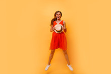 Portrait Of Excited Smiling Young Happy Jumping High Woman In Straw Summer Hat, Copy Space Isolated On Yellow Orange Background. People Sincere Emotions, Passion Lifestyle Concept. Advertising Area