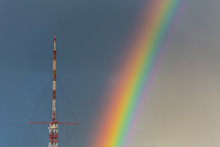 Big TV Relay Antenna Amid Blue Sky With Rainbow After Rain