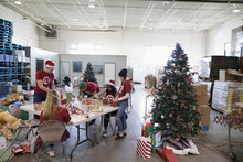 Volunteers Wrapping Christmas Gifts In Warehouse