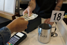 Close Up Customer Paying Cashier With Cash Next To Tip Jar