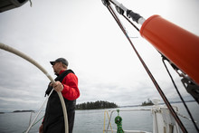 Man Steering Sailboat On Ocean
