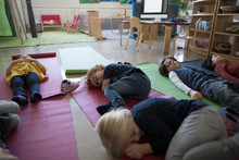 Tired Preschool Students Sleeping On Yoga Mats During Nap Time