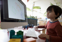 Focused Preschool Boy Drawing With Computer