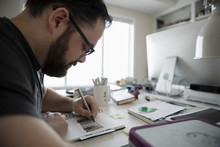 Focused Male Illustrator Sketching In Home Office