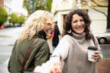 Playful Women Friends With Coffee On Street Corner