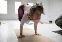 Focused Woman Practicing Yoga Crow Pose In Yoga Class