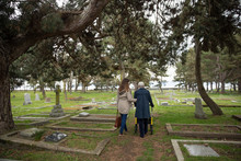 Daughter Walking With Senior Mother In Cemetery