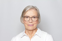 Portrait Picture Of A Senior Woman Wearing Glasses On Neutral Gray Background.