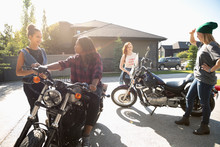 Young Women Friends With Motorcycles In Sunny Driveway