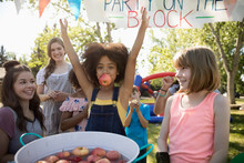 Portrait Playful Girl Bobbing For Apples At Summer Neighborhood Block Party In Park