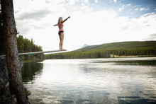Mature Woman On Diving Board Above Tranquil Lake, Alberta, Canada
