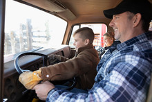 Male Farmer And Sons Driving Truck
