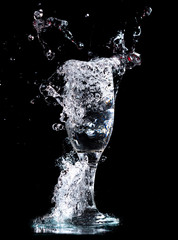 Wall Mural - Water with splashes in a glass on a black background