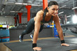 © New Africa - Young woman doing plank exercise in modern gym