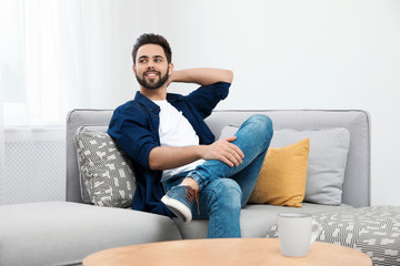 Wall Mural - Young man relaxing on couch at home