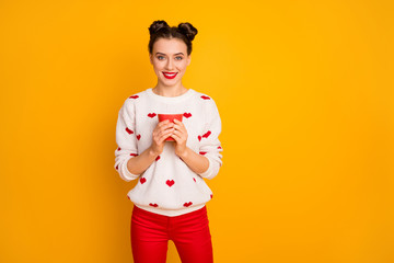 Poster - Photo of beautiful lady holding hot coffee beverage cup toothy smiling enjoy free time relaxation wear hearts pattern white sweater red pants isolated yellow color background