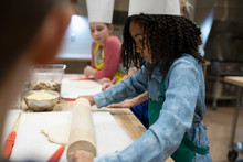 Focused Girl Rolling Out Pizza Dough In Cooking Class