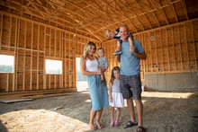 Portrait Happy Young Family Standing In Barn Under Construction
