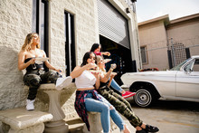 Latinx Young Women Friends Eating Lunch In Parking Lot