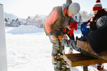 Father Tying Son's Ice Skates In Snow