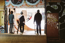 Teenage Skateboarders Watching Friend On Ramp At Indoor Skate Park