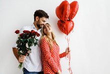 Couple. Love. Valentine's Day. Emotions. Man Is Giving Heart-shaped Balloons To His Woman, Both Smiling; On A White Background
