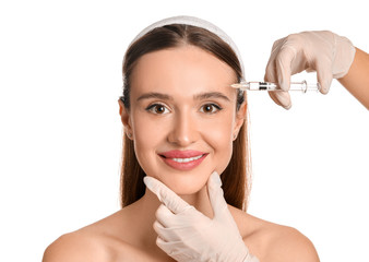 Wall Mural - Young woman receiving filler injection against white background