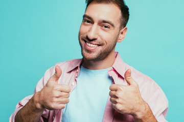 cheerful handsome man showing thumbs up, isolated on blue