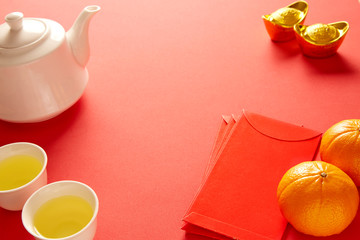 Chinese New Year and Lunar New Year celebrations with gold bar red envelope orange and hot tea. (with the character 