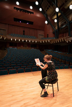 Female Performer Reviewing Notes On Stage In Empty Auditorium