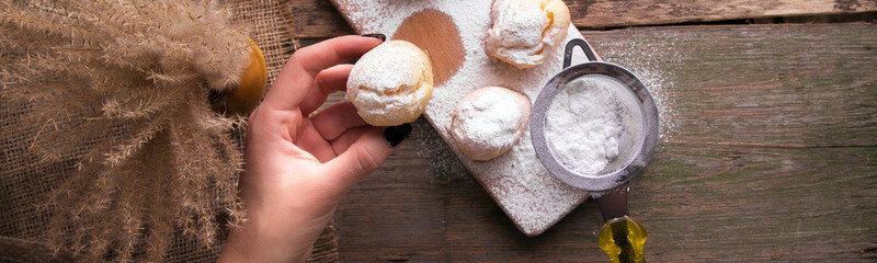 Banner with woman hand decorating with icing sugar some profiteroles.