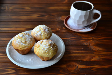 Cup of coffee and home made lemon muffins on a wooden table. Copy space.